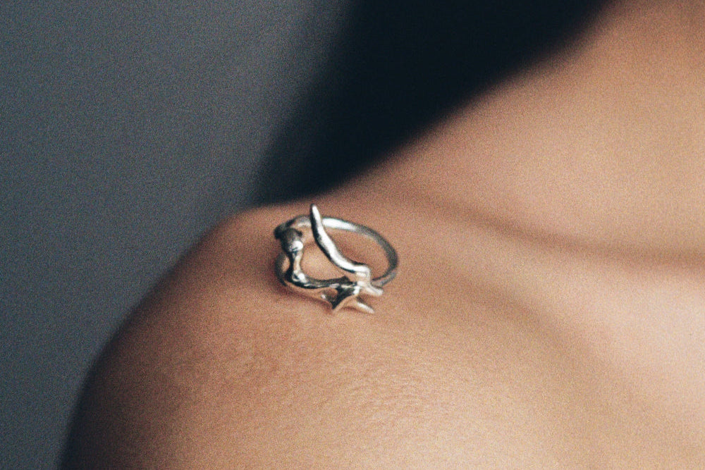 Silver ring on a person's shoulder against a dark background