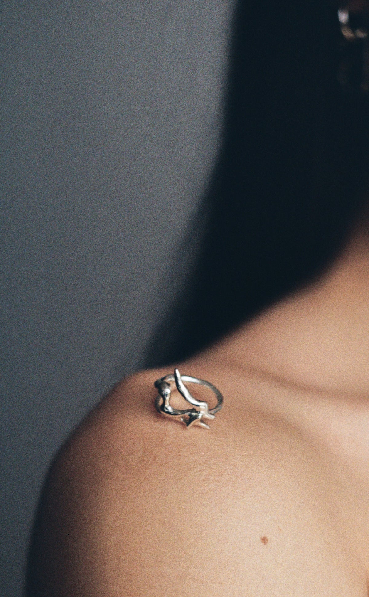 Silver ring on a person's shoulder against a dark background