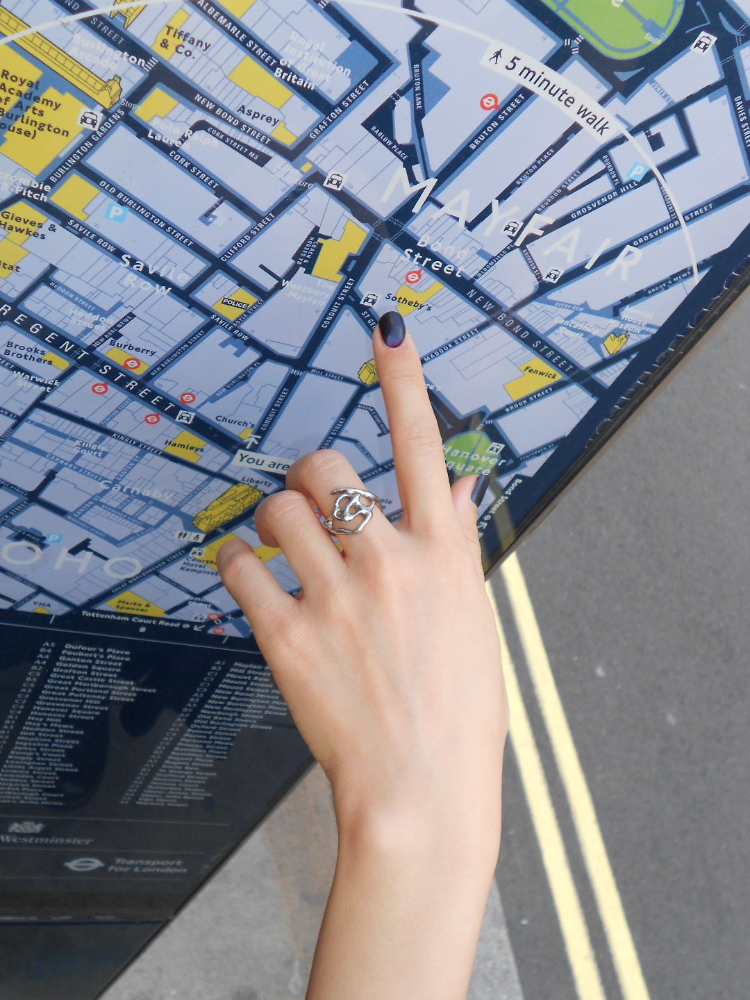 Hand with a ring pointing to a map on a street