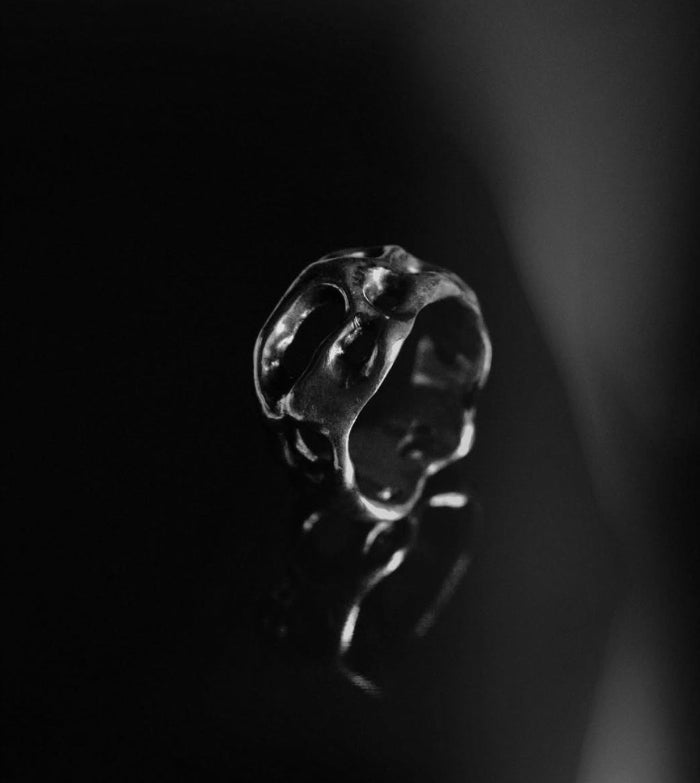 Silver ring with a unique design on a dark background